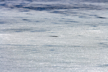 Fototapeta premium Quebec, Canada, 27 April 2026 : Close-up view of a frozen surface showing textured ice and subtle reflections under natural light.