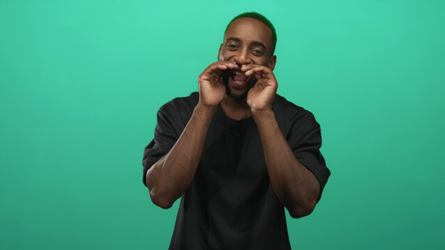Man cupping hands to mouth calling and smiling with visible braces in studio against a teal green backdrop; joyful energy.