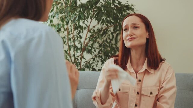 Upset woman crying with tissue during therapy session, showing emotional distress and need for psychological support and counseling