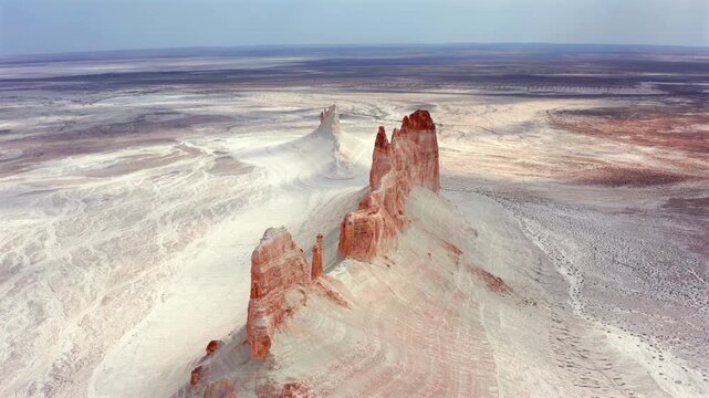 Aerial drone flying forward over Bozzhyra rock spires in Mangistau Kazakhstan, revealing vast white desert, ancient ocean floor and surreal canyon landscape formations