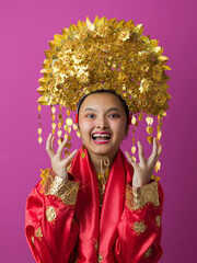 Naklejka premium Joyful Young Indonesian Asian Woman Wearing Traditional Chinese Gold Headdress And Red Silk Costume Celebrating Festival