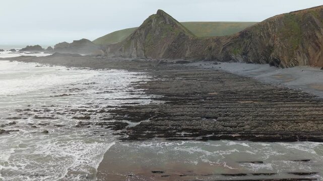 Aerial view of surroundings at Spekes Mill Mouth waterfall which is  located in a beautiful coast area of rugged valleys, high cliffs and wildflowers flourish. Drone POV of United Kingdom landscapes. 