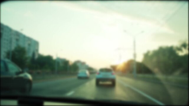 Soft focus perspective of car driving on multi-lane city highway at dusk. Blurred vehicle movement creates dynamic effect. Warm sunset colors illuminate horizon, offering peaceful, ambient backdrop.