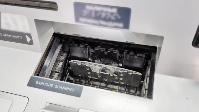 Close-up view of dollar bill engaged in automated teller machine mechanism, undergoing barcode scanning process. Scene illustrates modern financial technology and efficient banking transaction system.