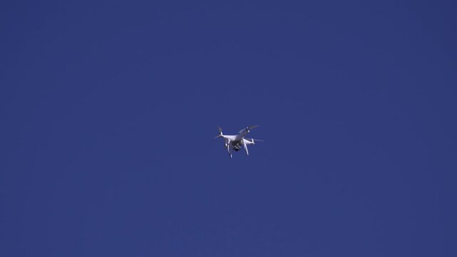 Unmanned aerial vehicle, quadcopter design, hovering against expansive blue sky. Technology for various applications like photography, mapping, or inspection.