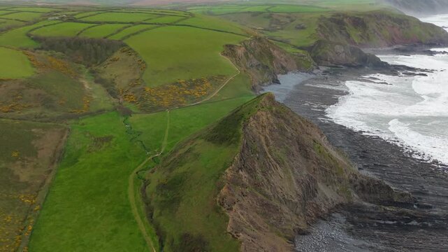 Aerial view of surroundings at Spekes Mill Mouth waterfall which is  located in a beautiful coast area of rugged valleys, high cliffs and wildflowers flourish. Drone POV of United Kingdom landscapes. 