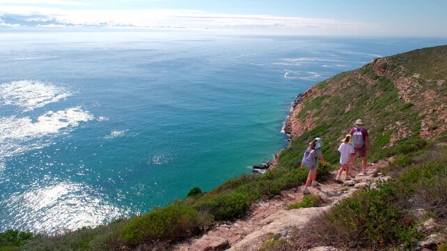 High angle view of two kids hiking with mother on Robberg Trail at sunrise