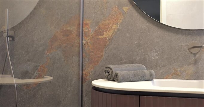 Premium interior with shower cabin ribbed wood vanity and round mirror, left to right camera pan reveals stone countertop integrated sink wall faucet bicolor stone look tiles black accessories