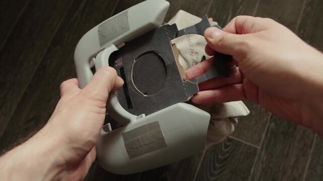 Hands performing replacement of dust bag inside vacuum cleaner. This essential household maintenance task ensures efficient operation of cleaning appliance. Focus on clean home and equipment care.