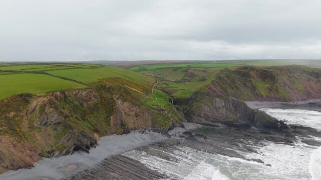 Aerial view of surroundings at Spekes Mill Mouth waterfall which is  located in a beautiful coast area of rugged valleys, high cliffs and wildflowers flourish. Drone POV of United Kingdom landscapes. 