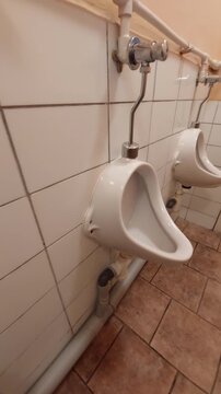 Public male restroom with white ceramic urinals and tiled wall