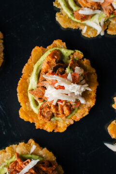 Top view of mini patacon with shredded chicken and cabbage slaw, crispy fried plantain latin appetizer concept