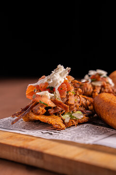 Mini patacones with shredded chicken, cheese and sauces on serving paper, crispy latin street food appetizer concept