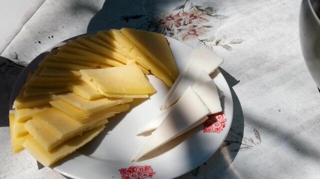 ​​cheese on a plate in the sunlight yellow cow and white goat cheese. High quality 4k footage