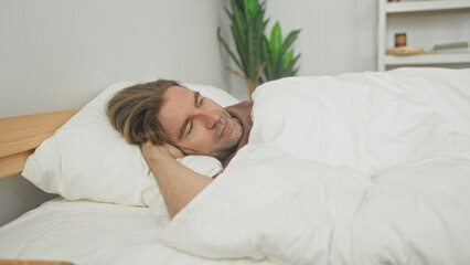 Man lying in bed with hand behind head on pillow under white duvet cover, bedroom  serenity contemplation. © Krakenimages.com