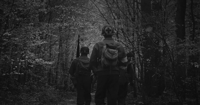 squad of Soviet military men and US soldiers walk through a green forest during World War II in historical uniforms