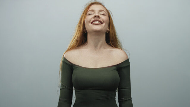 Woman with bare shoulders and exposed collarbones tilts head back, eyes closed and smiling in studio; serenity relief.