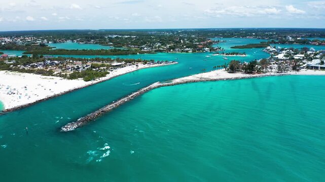 A jetty stretches into aquamarine waters near a coastal settlement. Ideal for travel and tourism content focusing on serene coastal landscapes.