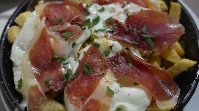 Traditional Spanish dish huevos rotos with fries, eggs, and cured ham, showcasing authentic cuisine, comfort food, and local dining experience ideal for food and restaurant concepts.