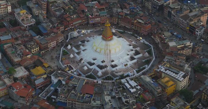 Aerial top view of Boudhanath Stupa, a UNESCO World Heritage Site in Kathmandu Nepal, centered within a circular plaza and surrounded by dense urban buildings and streets.