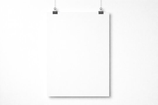 Vertical blank poster attached with metal clips against plain white background with copy space
