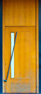 Closed brown wood entrance door with metal handle
