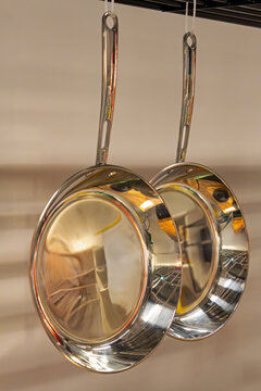 Empty silver fraying pans pans hanging from ceiling in store interior