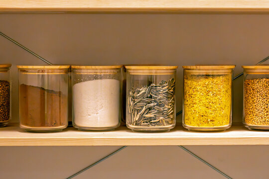Dry food ingredients inside plastic boxes on a shelf in home pantry
