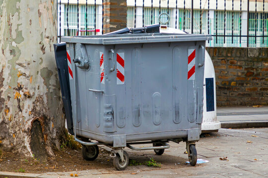 Closed metal garbage bin outside on urban city street pavement