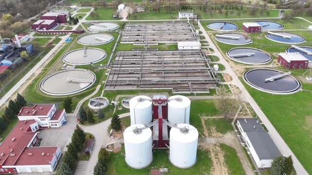 Aerial view of municipal wastewater treatment plant showing multiple circular tanks, filtration systems, and surrounding green areas, highlighting the infrastructure and operational layout of the faci