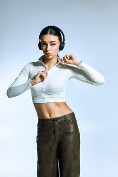 Trendy young woman showcasing stylish outfit in chic grey studio setting