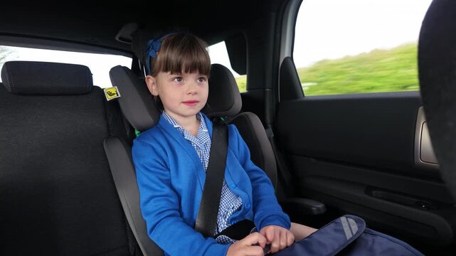 Young girl student traveling on school run drop off in a booster car seat