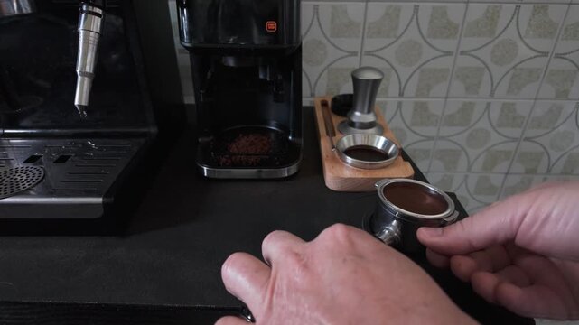 Professional barista tamping freshly ground coffee beans into a portafilter, preparing to brew a rich and aromatic espresso in a modern coffee shop or kitchen using specialized equipment