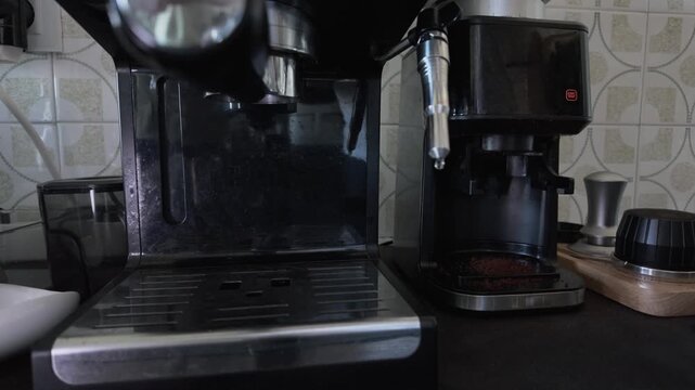 Barista using a professional machine to brew a fresh cup of espresso. The hot, dark beverage pours from the portafilter into a clear double walled glass, a daily ritual for a caffeine boost