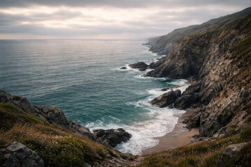 Fototapeta premium Quiet seaside vista presenting craggy cliffs and flowing waves under a subdued cloudy sky with copy space