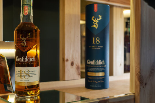 Bottle of Glenfiddich 18 Year Old Our Small Batch Eighteen single malt whisky on a mirror surface with its blue tube packaging on a wooden shelf. Ukraine, Zhytomyr, May 04, 2026
