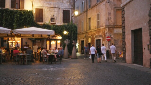 Defocused rome street with soft bokeh cobblestone and cafe terrace background; background, backplate, copyspace, calm.