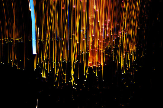Abstract golden light rain and glowing vertical streaks on dark background with long exposure photography