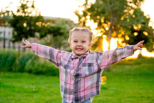 a child runs around playing on a green lawn in the summer, a little girl has fun outside, holidays, a happy child laughs