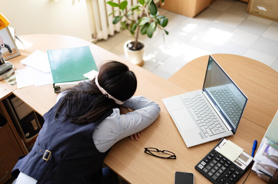 Business woman in a mask blindfolded asleep in the office. Exhausted employee in the workplace