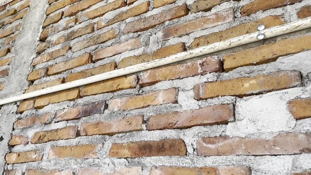 PVC Pipe Installation on Unfinished Red Brick Wall