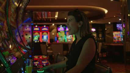 Woman cheering at slot machine in casino building, fists raised and smiling at winning spin  joy luck winning. © Krakenimages.com