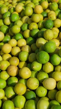 close-up of a large pile of fresh yellow and green lemons at a wholesale market