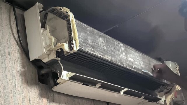 Detailed split AC filter cleaning process by skilled technician ensuring proper cooling and air circulation indoors. Professional HVAC maintenance footage suitable for appliance repair, 