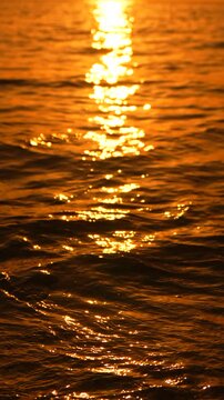 Sunset ocean reflections shimmering on gentle waves washing onto a sandy beach shore at golden hour