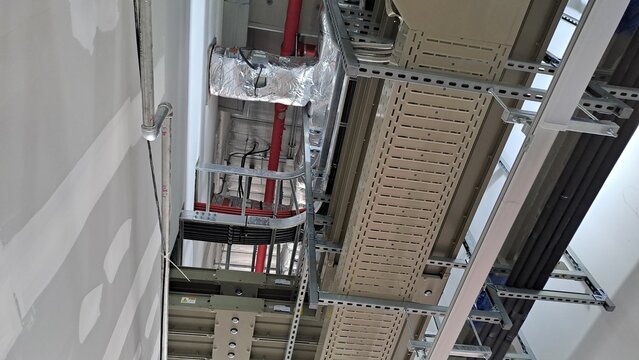 complex industrial ceiling infrastructure with cable trays and insulated piping in a data center