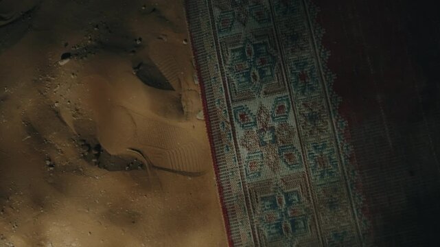 traditional patterned kilim rug border meeting bare desert sand ground at night in camp