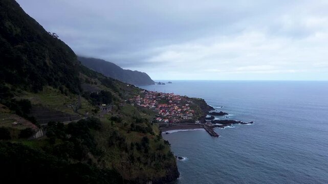 Aerial drone shot of dramatic mountainous terrain in the Rabacal region on Madeira Island, Portugal featuring steep valley walls, lush green vegetation, waterfalls, and rugged volcanic rock formations