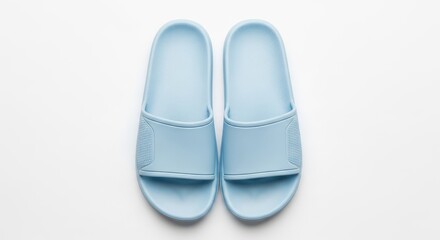 Fototapeta premium Simple light blue slide sandals resting on a clean white surface, perfect for summer comfort.