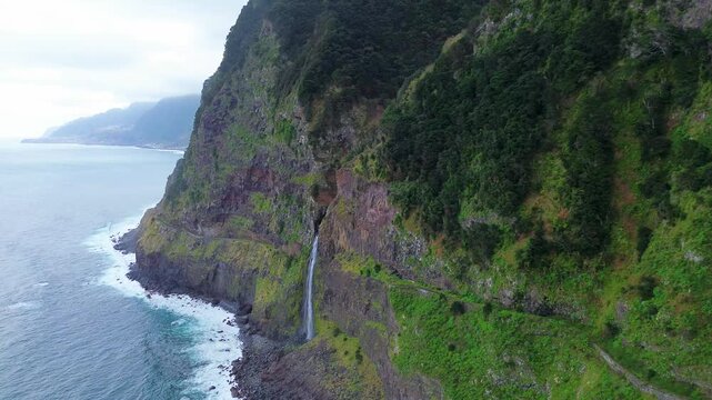 Aerial static shot captures the dramatic Veu da Noiva waterfall dropping down a steep cliff on the north coast near Seixal on Madeira island, Portugal.